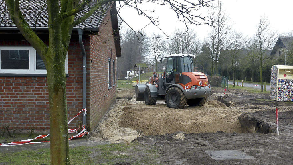 Ein Bagger schiebt auf der Baustelle der Kinderkrippe des ASB Diepholz Sand in die Baugrube.